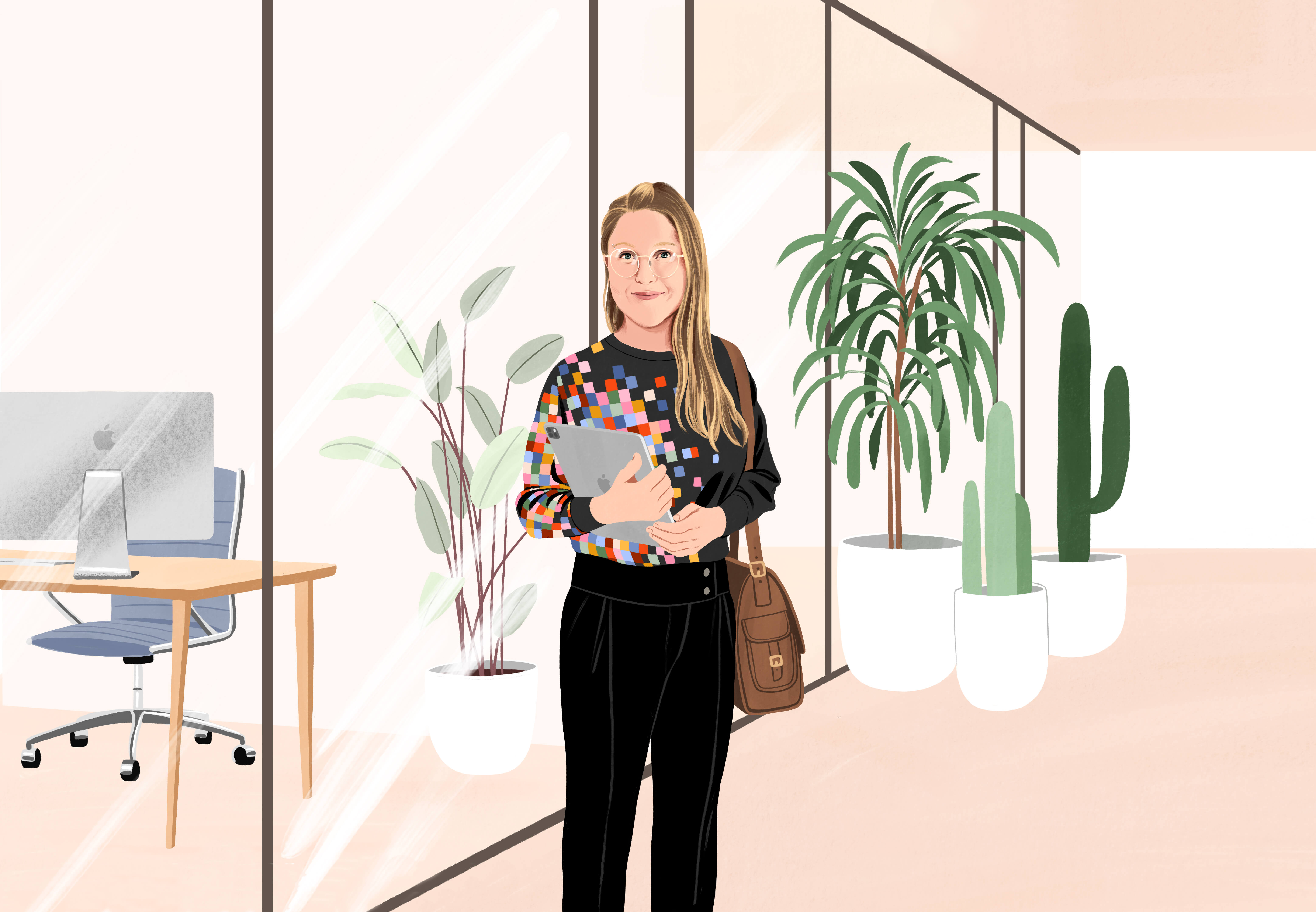 Manuela stands smiling in an office hallway, holding an iPad with a book bag on her shoulder. She’s wearing black pants and a black shirt with a colourful pixel pattern across one side.
