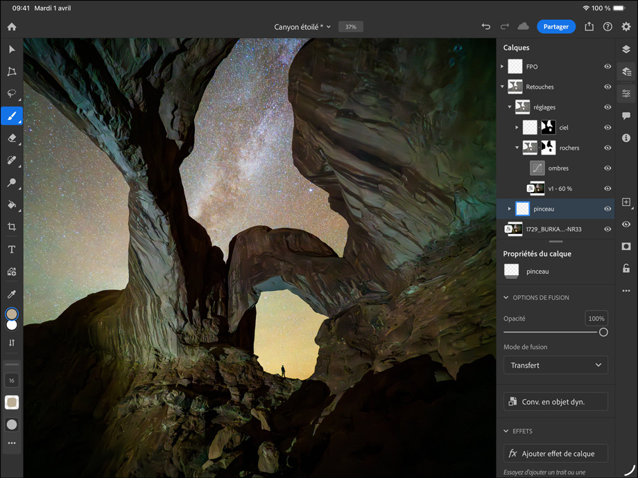 iPad Pro, face avant, orientation paysage, noir sidéral, angles arrondis, cadre d’écran noir, écran affichant la retouche d’une photo d’un canyon et d’un ciel étoilé, avec sur la droite, calques de retouche, outils et effets visibles, notamment pinceau, réglages et autres
