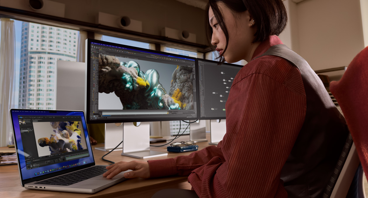 Asmuo, sėdintis ofisą primenančioje aplinkoje, dirba su „MacBook“ nešiojamuoju kompiuteriu, kuris yra prijungtas prie „Studio Display XDR“ naudojant „Thunderbolt 5“ prievadą