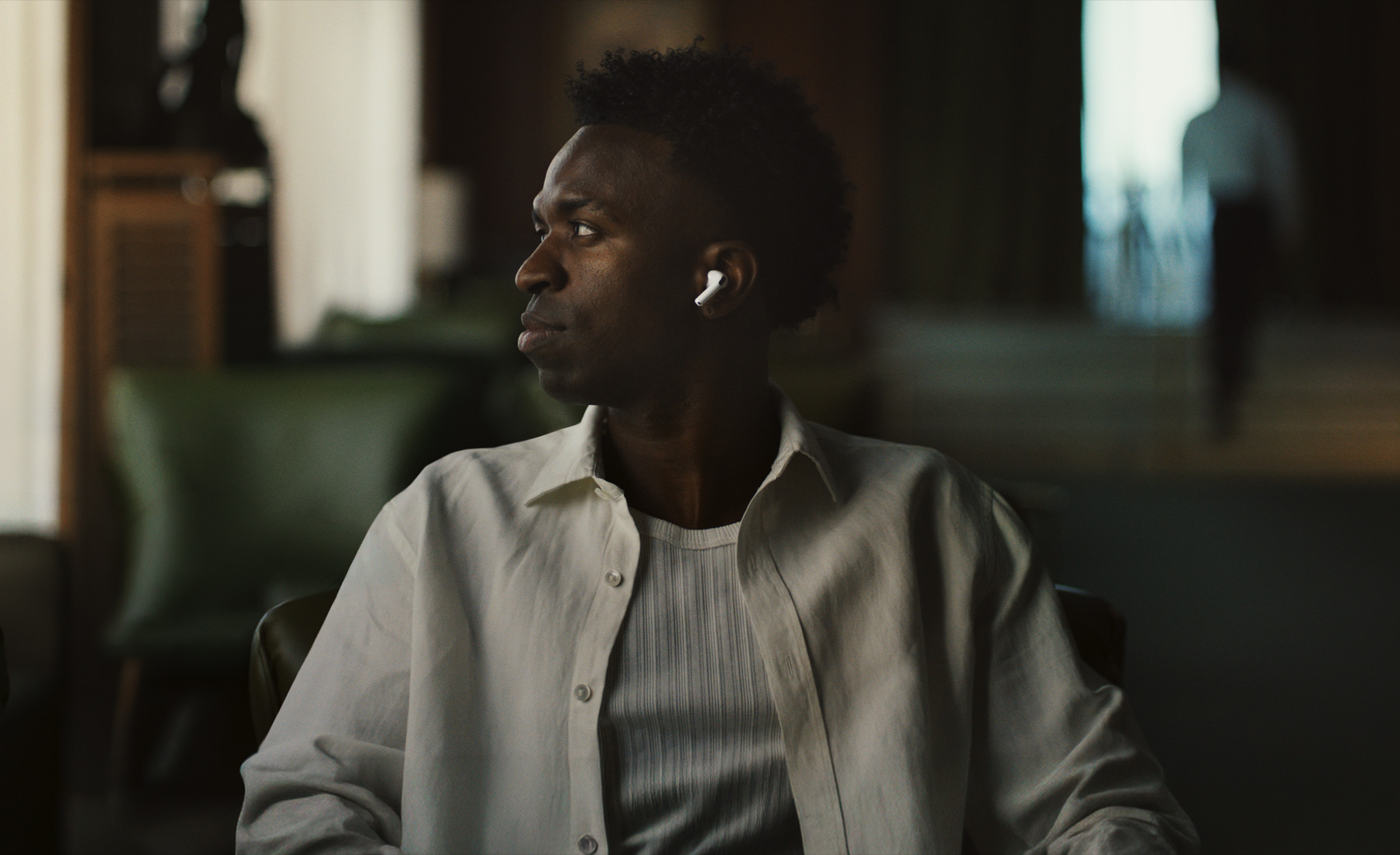 Una persona con una camisa blanca, se ve el audífono izquierdo de los AirPods Pro 3