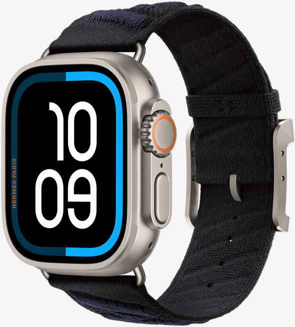 Apple Watch Hermès Ultra 3, boîtier en titane, finition naturelle, écran bord à bord, angles arrondis, côté droit, Digital Crown, micro, bouton latéral en saillie, cadran numérique (chiffres des heures et des minutes indiquant 10:09), associée au bracelet En Mer, noir/bleu nuit (noir avec rayures texturées diagonales bleu foncé), mailles tricotées en fil polyamide, trous d’ajustement centrés, attaches et boucle en titane finition naturelle