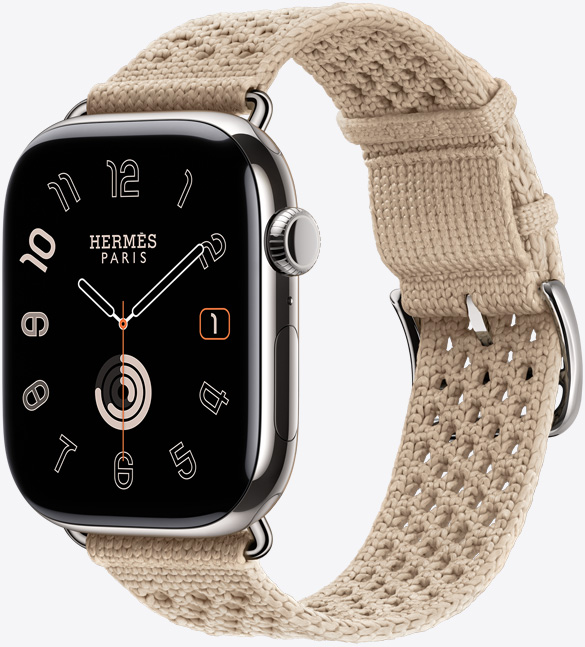 Apple Watch Hermès Series 11, boîtier en titane, argent, fini poli, écran bord à bord, angles arrondis, côté droit, Digital Crown, micro, bouton latéral, cadran Circulaire (aiguilles des heures, des minutes et des secondes, logo Hermès Paris), associée au bracelet Néo Tricot, argile (beige), mailles tricotées en fil polyamide, trous d’ajustement centrés, attaches et boucle argent