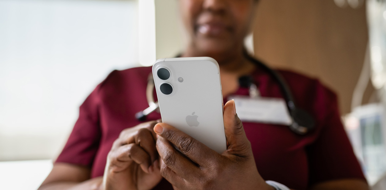 Un’infermiera in camice rosso mentre guarda il suo iPhone.